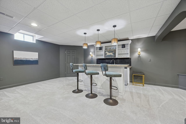 bar with light colored carpet, visible vents, baseboards, hanging light fixtures, and wet bar