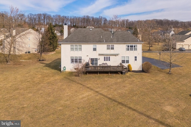 back of house with a chimney, a deck, a lawn, and stucco siding