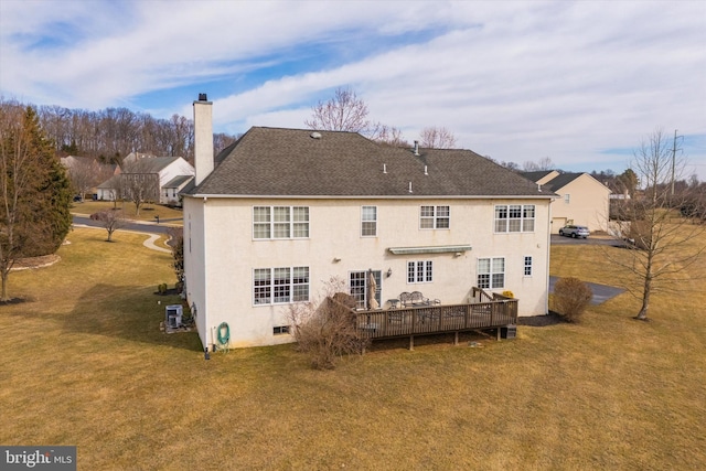 rear view of property featuring stucco siding, a wooden deck, a chimney, and a yard