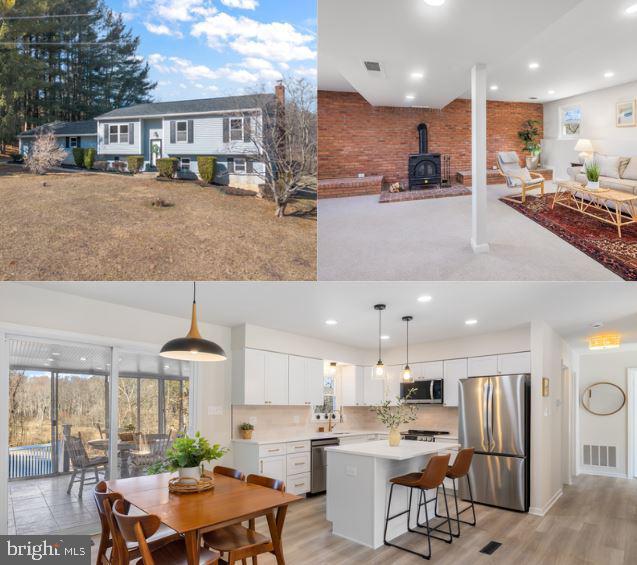 interior space with stainless steel appliances, a wood stove, visible vents, and white cabinetry