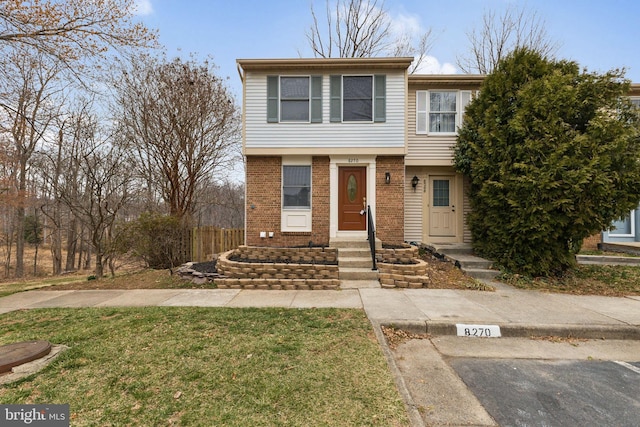 townhome / multi-family property with brick siding and a front yard