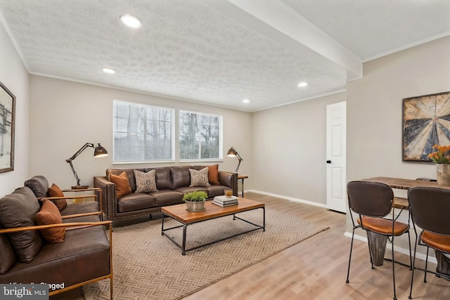 living area featuring light wood-style flooring, a textured ceiling, baseboards, and ornamental molding