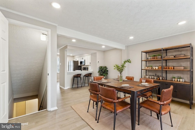 dining area with recessed lighting, light wood-type flooring, baseboards, and a textured ceiling