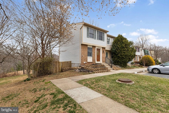 view of front of house with brick siding, a front lawn, and fence