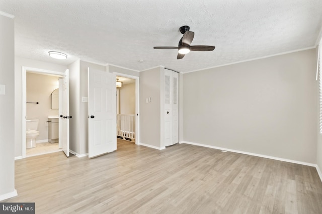 unfurnished bedroom featuring light wood-style flooring, baseboards, a closet, and a textured ceiling