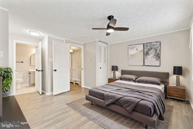 bedroom with light wood-style flooring, ensuite bathroom, a textured ceiling, a closet, and baseboards