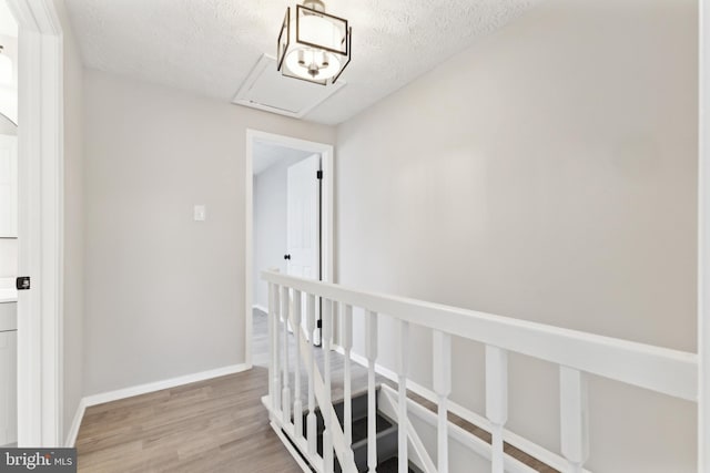 hallway featuring a textured ceiling, baseboards, and light wood-style floors