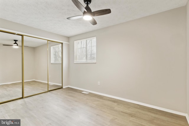 unfurnished bedroom with a closet, baseboards, a textured ceiling, and wood finished floors