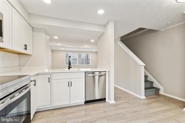 kitchen featuring a sink, light countertops, white cabinets, light wood-style floors, and appliances with stainless steel finishes