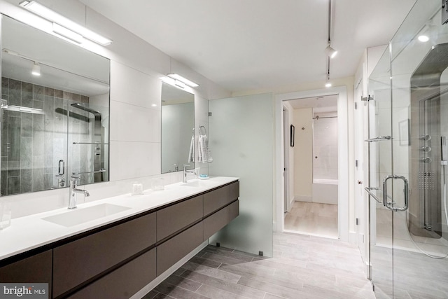 bathroom with double vanity, a shower stall, and a sink