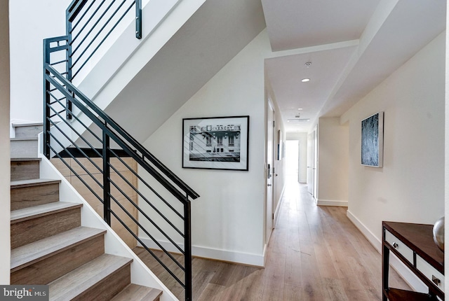 stairway featuring recessed lighting, wood finished floors, and baseboards