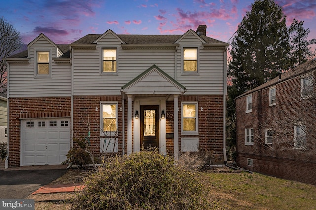 view of front of property with brick siding, an attached garage, and aphalt driveway