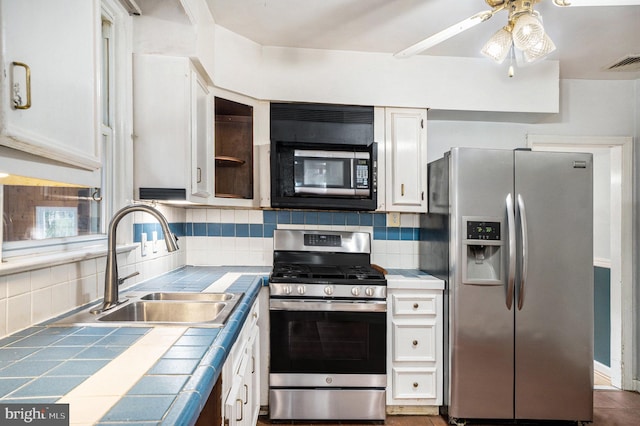 kitchen with visible vents, backsplash, tile countertops, stainless steel appliances, and a sink