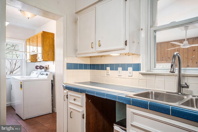 kitchen with washer and dryer, decorative backsplash, white cabinetry, and a sink