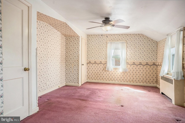 carpeted spare room with wallpapered walls, vaulted ceiling, and ceiling fan