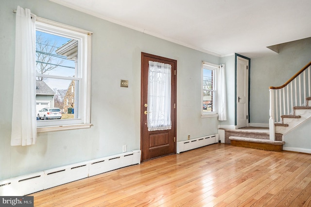 foyer featuring ornamental molding, stairs, light wood-type flooring, and a baseboard radiator