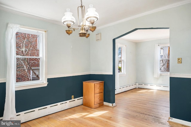 unfurnished room featuring a chandelier, ornamental molding, a baseboard heating unit, and wood finished floors