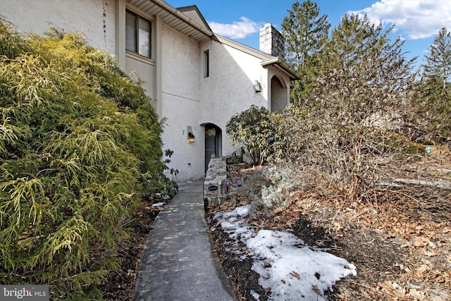 view of side of home featuring a chimney and stucco siding