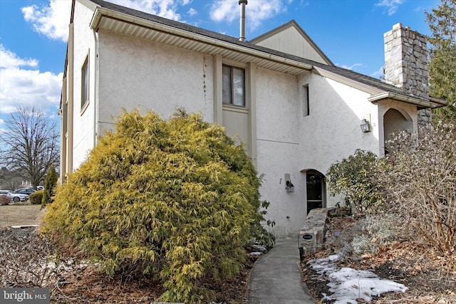 view of front of property featuring a chimney and stucco siding