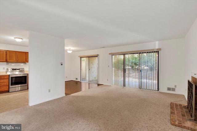 unfurnished living room with baseboards, a brick fireplace, visible vents, and light colored carpet