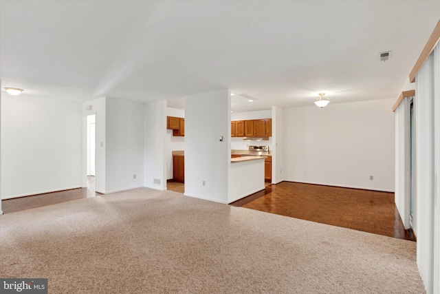 unfurnished living room featuring baseboards, visible vents, and dark colored carpet