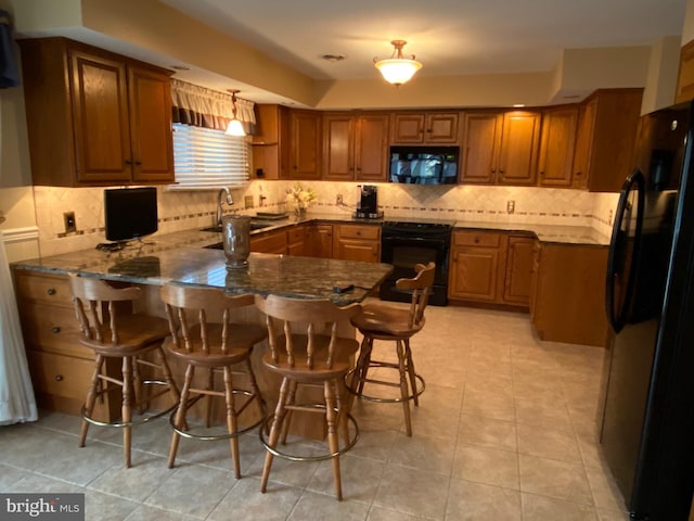 kitchen with a peninsula, black appliances, brown cabinetry, and a sink