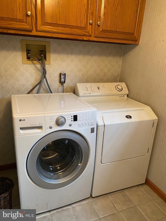 laundry room featuring wallpapered walls, light tile patterned floors, cabinet space, baseboards, and washer and clothes dryer