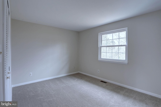 carpeted spare room with visible vents and baseboards