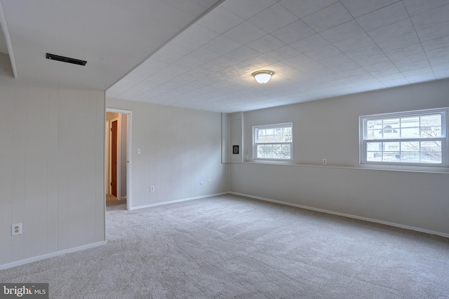 spare room featuring carpet, visible vents, and baseboards