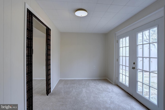 carpeted empty room featuring french doors and baseboards