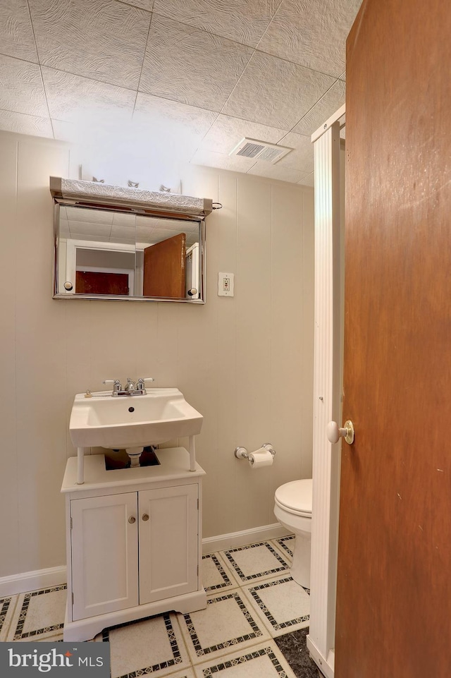 bathroom featuring visible vents, toilet, vanity, and baseboards