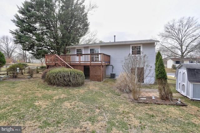 rear view of property with a wooden deck, a lawn, an outdoor structure, and a shed