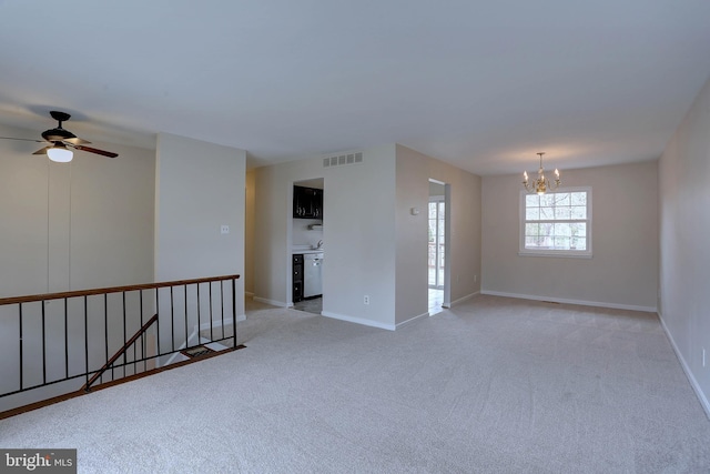 unfurnished room with visible vents, baseboards, light colored carpet, and ceiling fan with notable chandelier