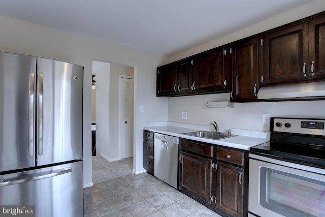 kitchen with under cabinet range hood, dark brown cabinetry, light countertops, stainless steel appliances, and a sink