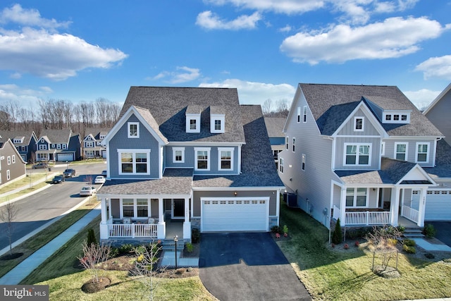 view of front facade featuring aphalt driveway, a shingled roof, covered porch, an attached garage, and a residential view