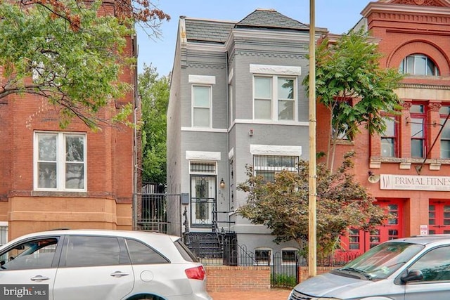 view of front facade with brick siding and fence