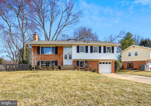 raised ranch featuring a front lawn, driveway, fence, brick siding, and a chimney