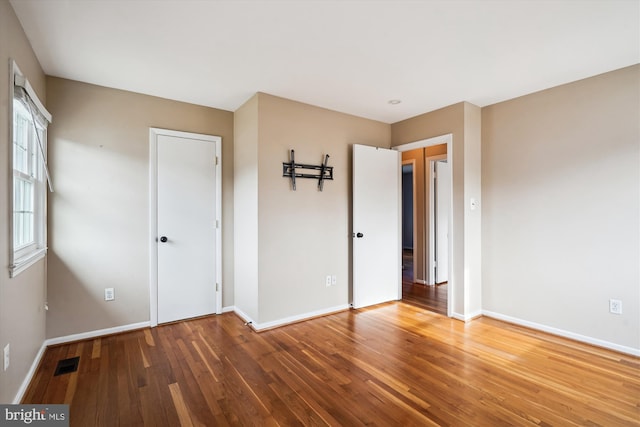 unfurnished bedroom featuring visible vents, baseboards, and hardwood / wood-style flooring