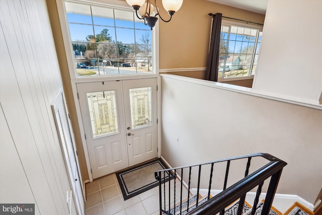 tiled entryway featuring baseboards, an inviting chandelier, and stairs