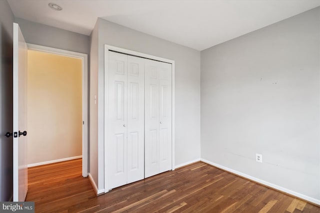 unfurnished bedroom with a closet, baseboards, and wood finished floors