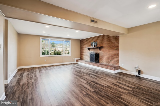 unfurnished living room with a fireplace, dark wood-style floors, visible vents, and baseboards