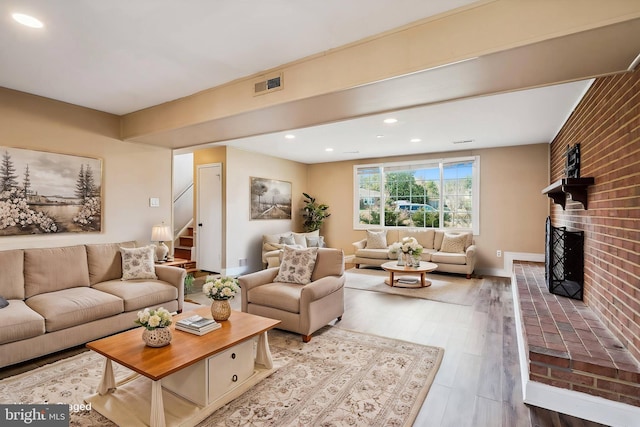 living area featuring visible vents, wood finished floors, stairway, a fireplace, and baseboards