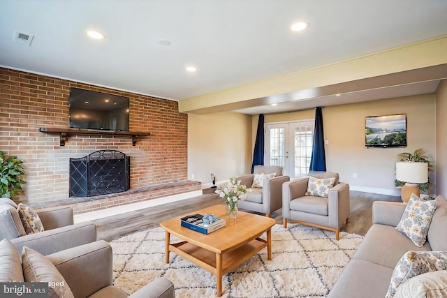 living area with a brick fireplace, recessed lighting, wood finished floors, and french doors