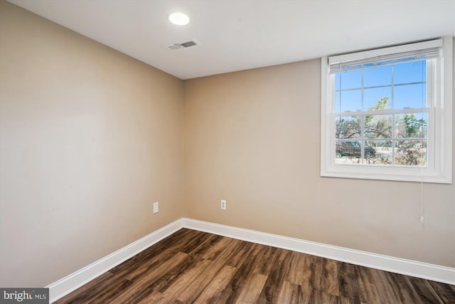 spare room featuring visible vents, baseboards, and dark wood-style flooring