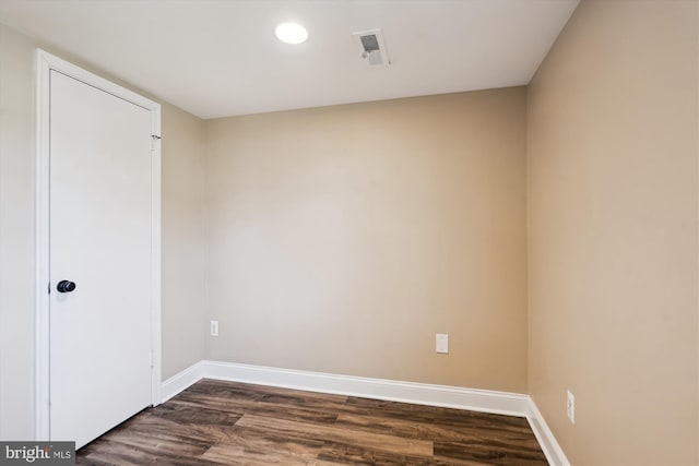 empty room featuring visible vents, baseboards, and dark wood-style flooring