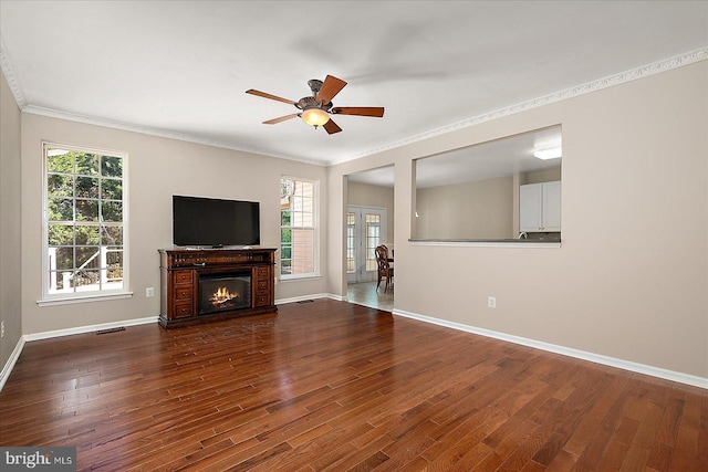 unfurnished living room featuring crown molding, baseboards, ceiling fan, and wood finished floors