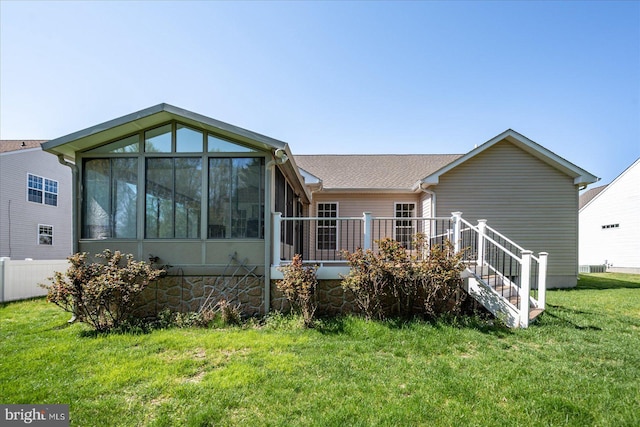 rear view of house featuring stairway, a deck, a sunroom, and a lawn