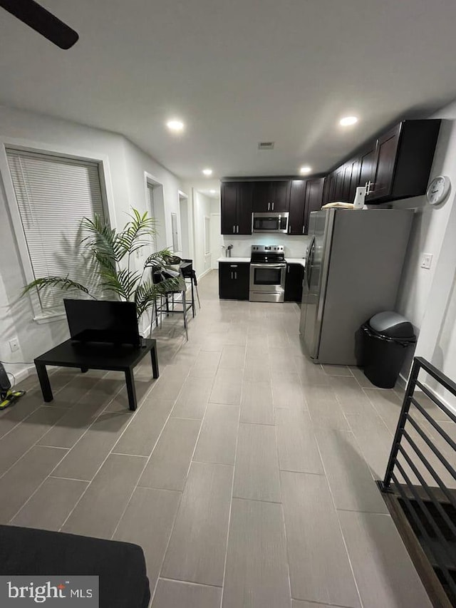 kitchen featuring appliances with stainless steel finishes, light countertops, dark cabinets, and recessed lighting