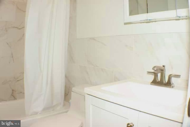 full bath with a shower with shower curtain, vanity, tile walls, and toilet