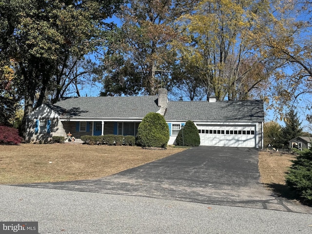 view of front of home featuring an attached garage, a chimney, and aphalt driveway